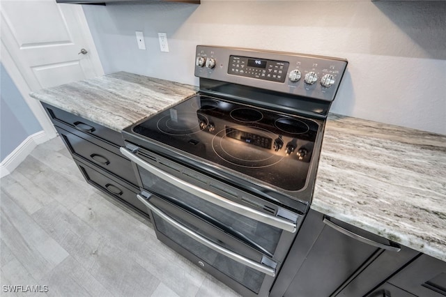 kitchen with light stone counters, stainless steel electric range, and light wood-type flooring