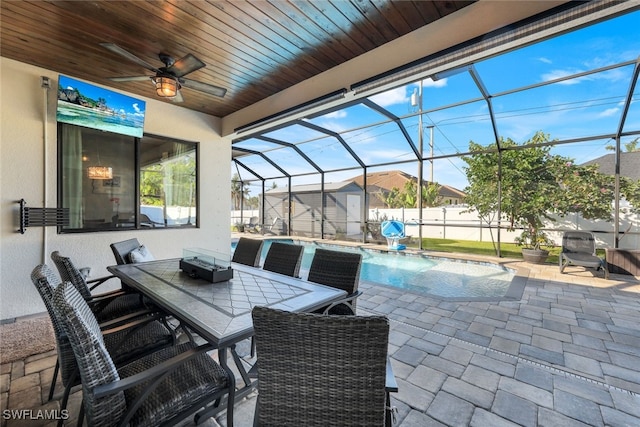 view of patio with pool water feature, glass enclosure, ceiling fan, a storage unit, and a fenced in pool