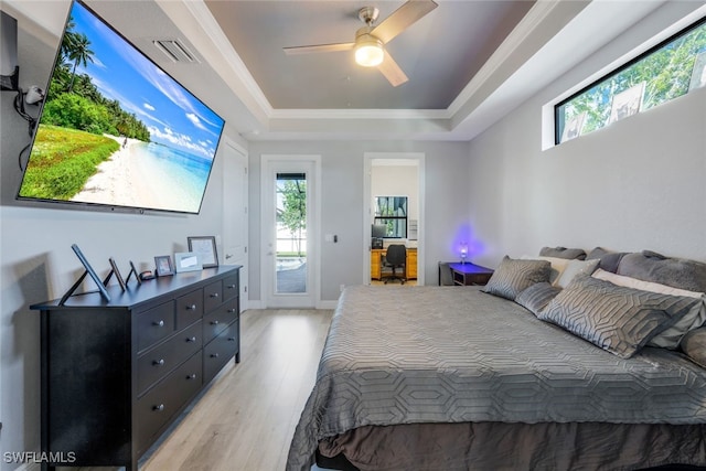 bedroom featuring a raised ceiling, access to outside, multiple windows, and light wood-type flooring