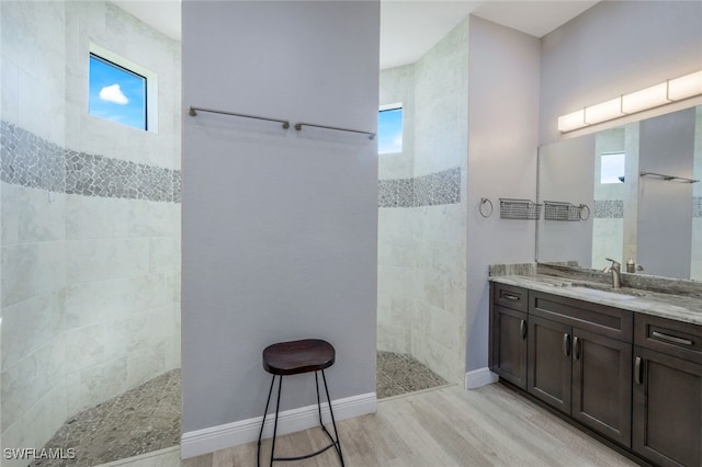 bathroom with hardwood / wood-style flooring, vanity, and a tile shower