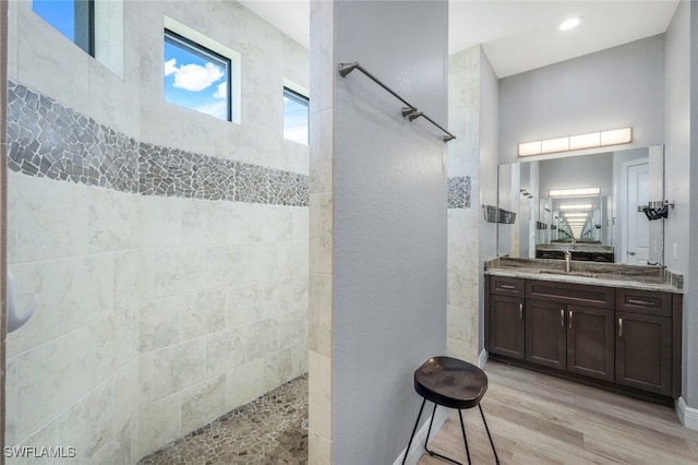 bathroom with vanity, hardwood / wood-style flooring, and a tile shower