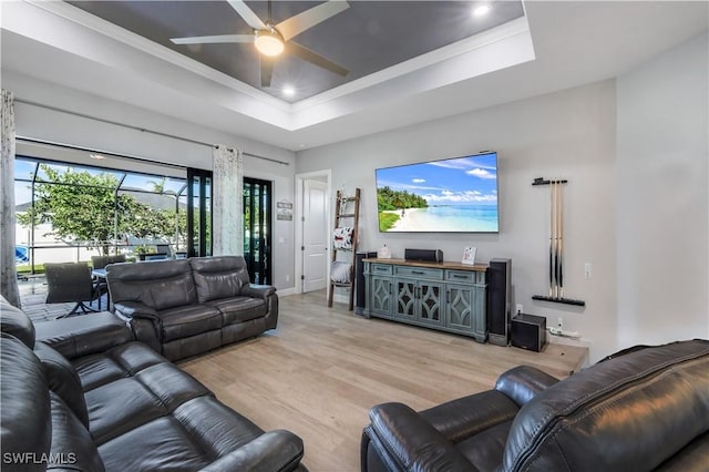 living room featuring ceiling fan, ornamental molding, a raised ceiling, and light hardwood / wood-style floors