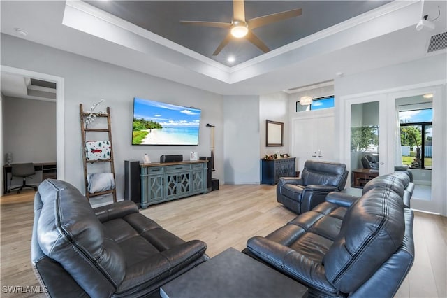 living room with ornamental molding, ceiling fan, light hardwood / wood-style floors, and a tray ceiling