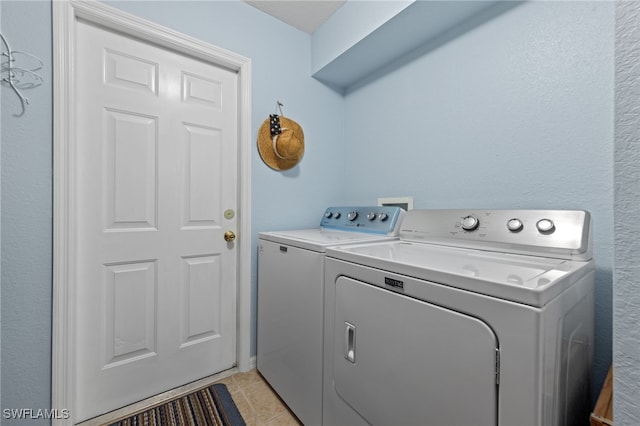 clothes washing area with independent washer and dryer and light tile patterned floors