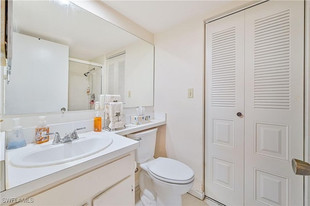 bathroom featuring a shower with door, vanity, and toilet