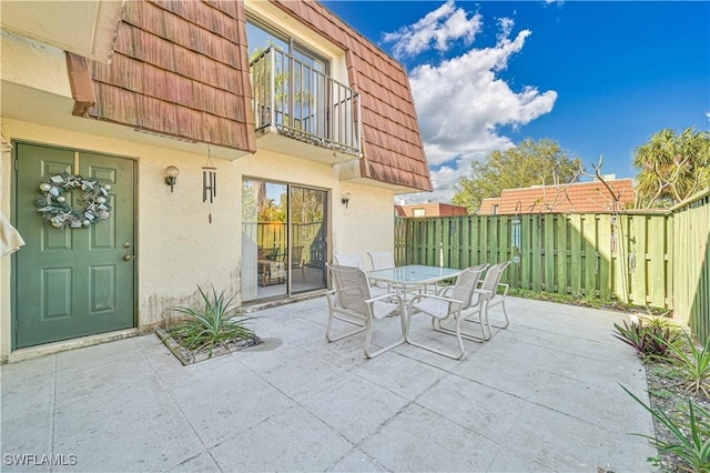 view of patio / terrace with fence, outdoor dining space, and a balcony