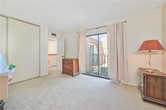 unfurnished bedroom featuring a textured ceiling, access to outside, and light carpet