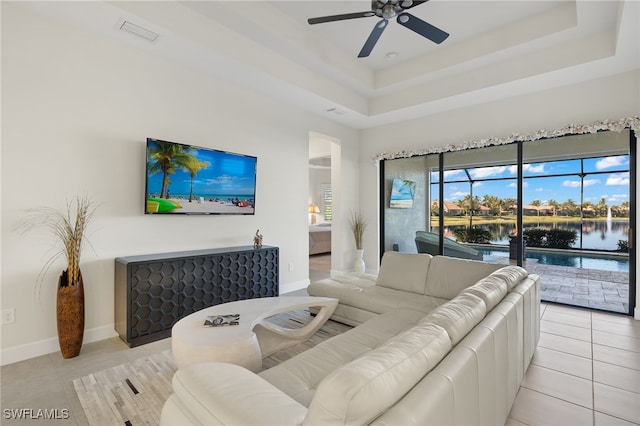 living room featuring ceiling fan, light tile patterned floors, and a tray ceiling