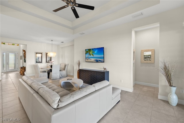 living room featuring light tile patterned floors, a tray ceiling, and ceiling fan