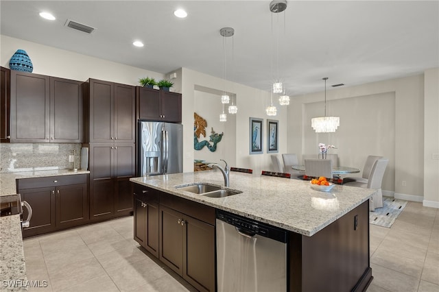 kitchen featuring a center island with sink, sink, hanging light fixtures, dark brown cabinets, and stainless steel appliances