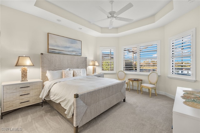 carpeted bedroom with a tray ceiling and ceiling fan