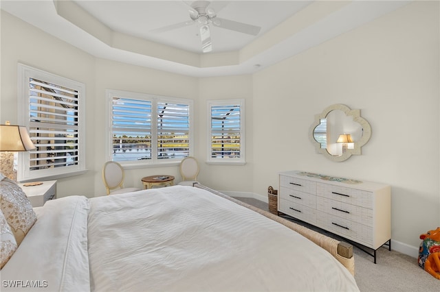 carpeted bedroom featuring a tray ceiling and ceiling fan