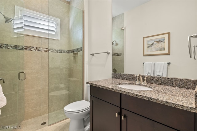 bathroom featuring tile patterned flooring, vanity, toilet, and an enclosed shower