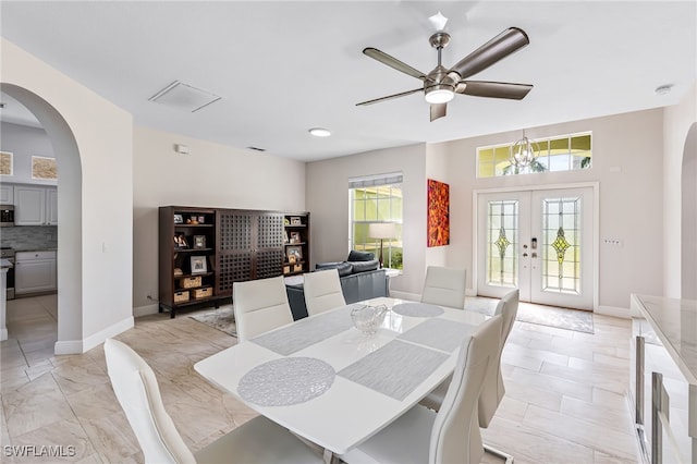 dining room featuring french doors and ceiling fan with notable chandelier