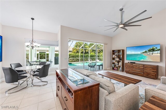 living room with ceiling fan with notable chandelier, light tile patterned flooring, and vaulted ceiling