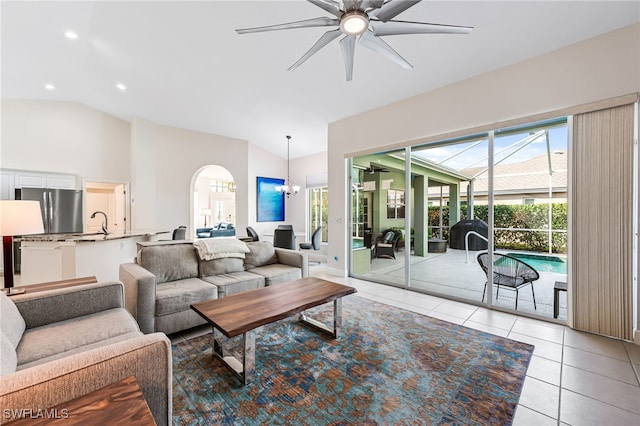 living room with ceiling fan with notable chandelier, sink, light tile patterned floors, and vaulted ceiling