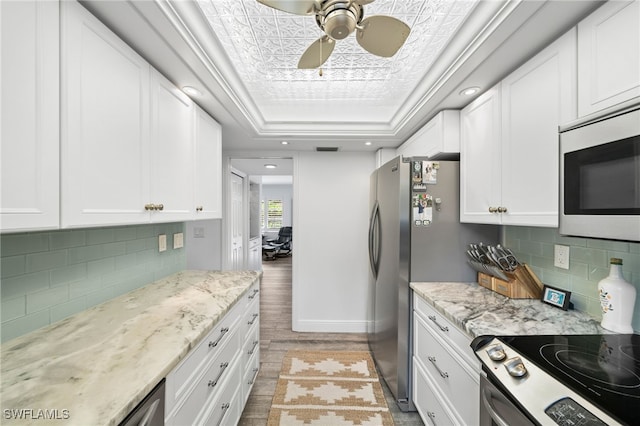 kitchen featuring a tray ceiling, light hardwood / wood-style flooring, white cabinets, and stainless steel appliances