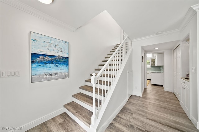 staircase featuring crown molding and wood-type flooring