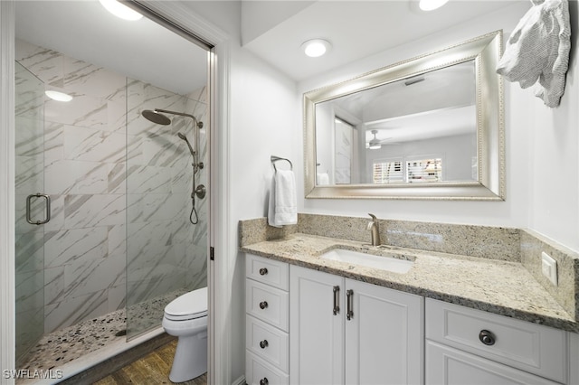 bathroom featuring hardwood / wood-style floors, vanity, a shower with door, ceiling fan, and toilet