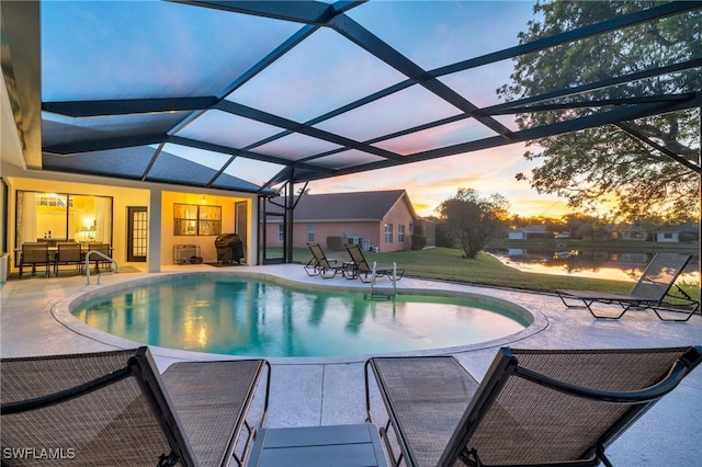 pool at dusk featuring a lanai and a patio