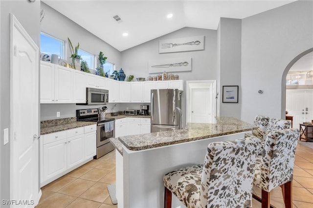 kitchen with white cabinetry, light tile patterned flooring, dark stone counters, and appliances with stainless steel finishes