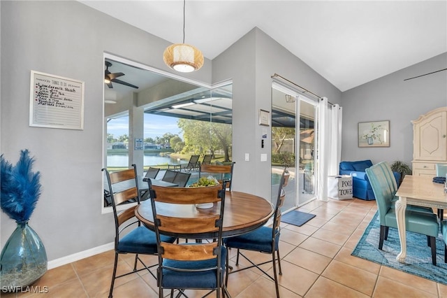 tiled dining area with ceiling fan, plenty of natural light, a water view, and vaulted ceiling