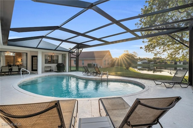 view of swimming pool with glass enclosure, a patio area, and a water view