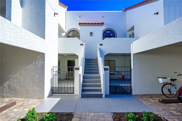 doorway to property with stucco siding, a tile roof, and a gate