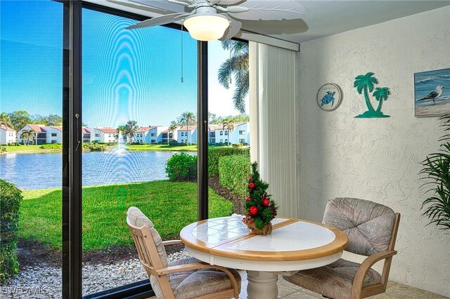 sunroom featuring ceiling fan and a water view