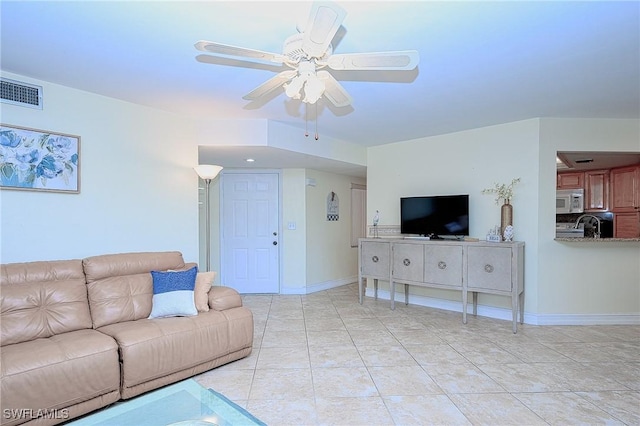 living area featuring light tile patterned floors, a ceiling fan, visible vents, and baseboards