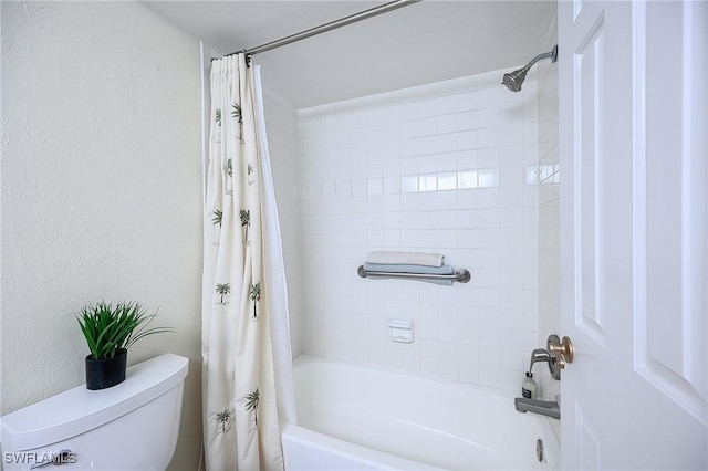 bathroom featuring shower / bathtub combination with curtain, toilet, and a textured wall