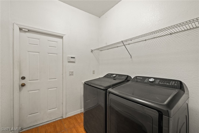 clothes washing area with independent washer and dryer and wood-type flooring