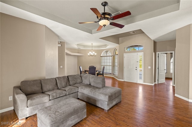 living room featuring a raised ceiling, dark hardwood / wood-style flooring, and ceiling fan with notable chandelier