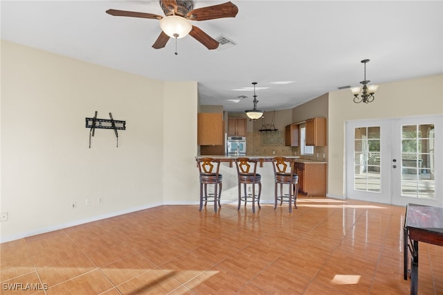 kitchen with stainless steel oven, french doors, hanging light fixtures, kitchen peninsula, and decorative backsplash