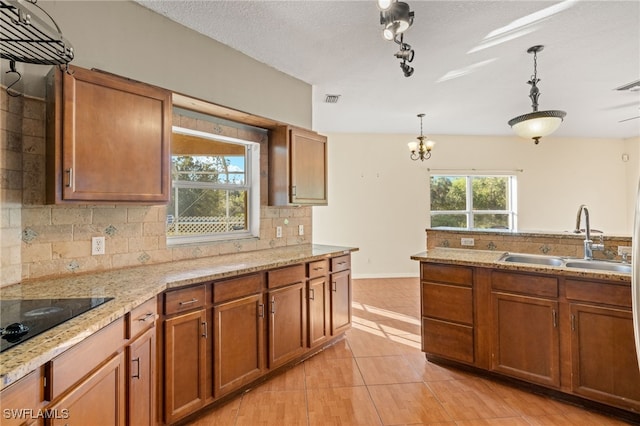 kitchen featuring black electric cooktop, decorative light fixtures, tasteful backsplash, and sink