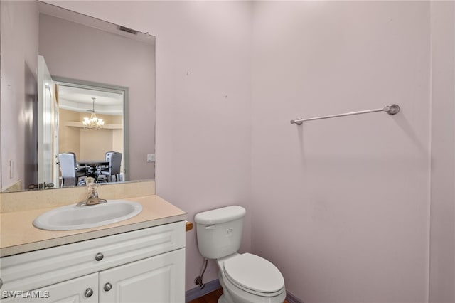 bathroom featuring vanity, an inviting chandelier, and toilet