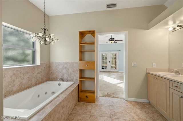 bathroom featuring french doors, vanity, vaulted ceiling, tiled tub, and tile patterned flooring