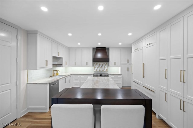 kitchen featuring white cabinets, backsplash, hardwood / wood-style flooring, and wall chimney exhaust hood