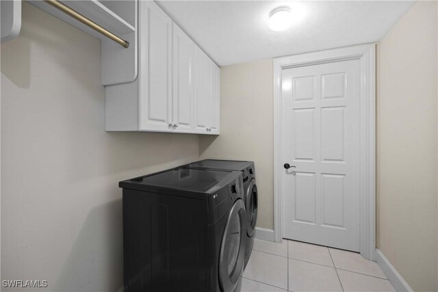 washroom with washer and clothes dryer, cabinets, and light tile patterned floors