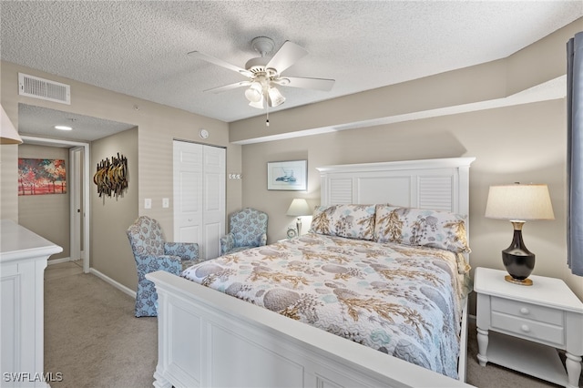 carpeted bedroom with ceiling fan, a textured ceiling, and a closet