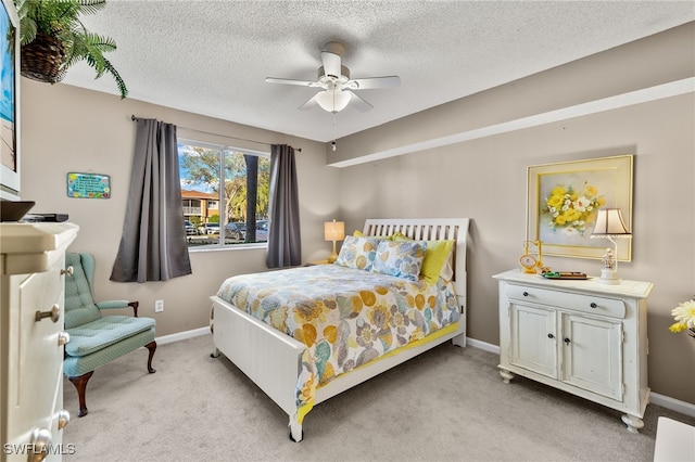 bedroom featuring a textured ceiling, light colored carpet, and ceiling fan