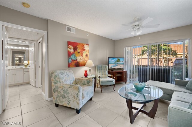 living room with ceiling fan, light tile patterned flooring, and a textured ceiling