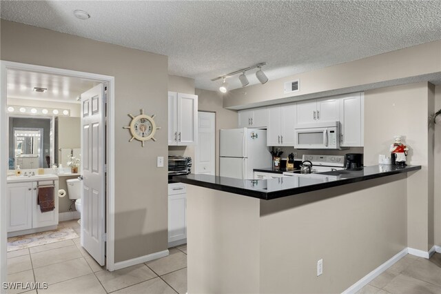 kitchen featuring a textured ceiling, white cabinetry, white appliances, and kitchen peninsula