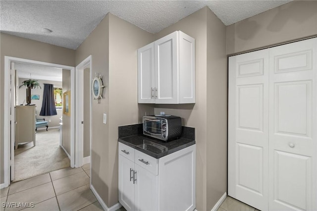 kitchen featuring a textured ceiling, white cabinetry, and light tile patterned flooring