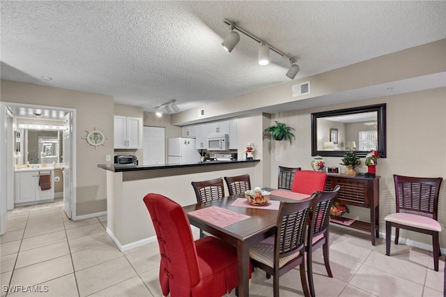 dining space with light tile patterned floors, track lighting, and a textured ceiling