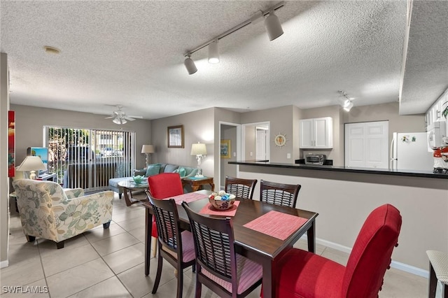 dining area with a textured ceiling, ceiling fan, light tile patterned floors, and track lighting