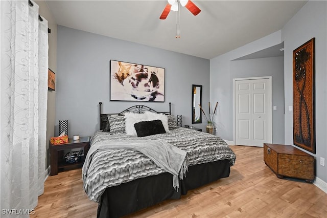 bedroom with a ceiling fan, baseboards, and light wood finished floors