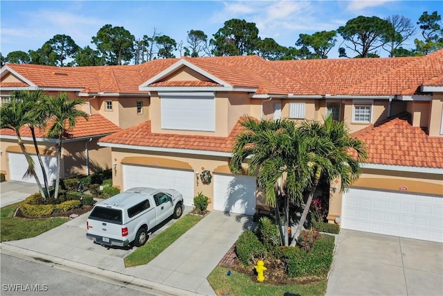 view of front of property with a garage, a tiled roof, concrete driveway, and stucco siding