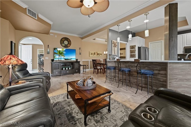 living area with baseboards, visible vents, arched walkways, ceiling fan, and crown molding