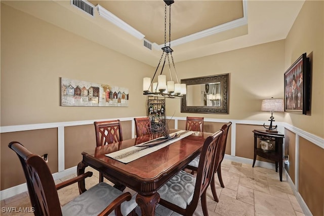 dining area featuring a wainscoted wall, a raised ceiling, visible vents, and stone tile floors